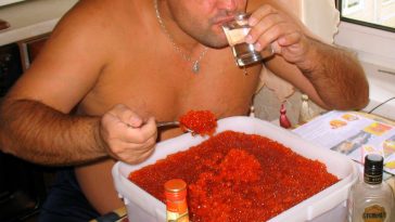 shirtless russian man eating tub of caviar